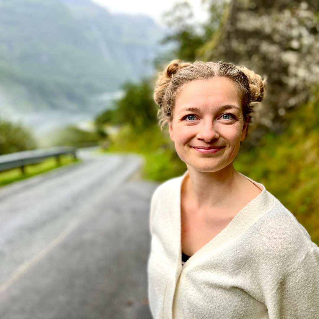 Marie Eckert Medisaurier Lächelnde Frau steht vor Straße im Grünen